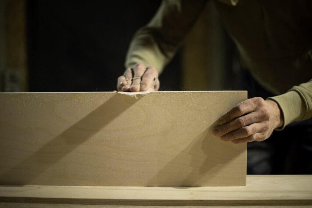 man sanding a wooden board