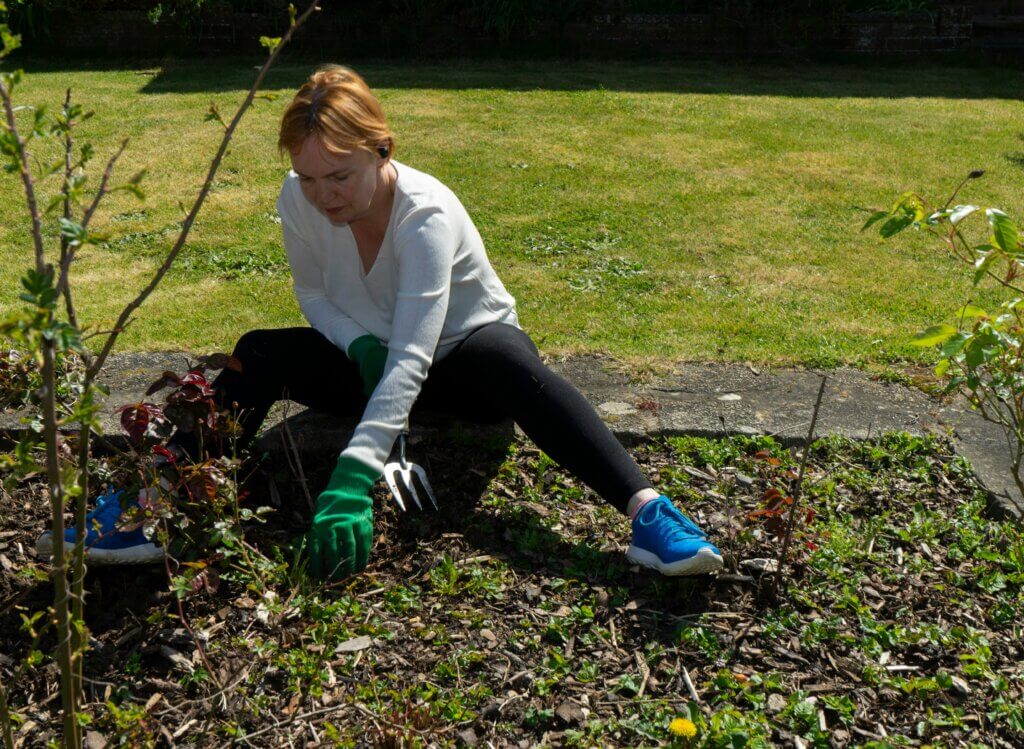 Lady removing weeds from soil in a garden