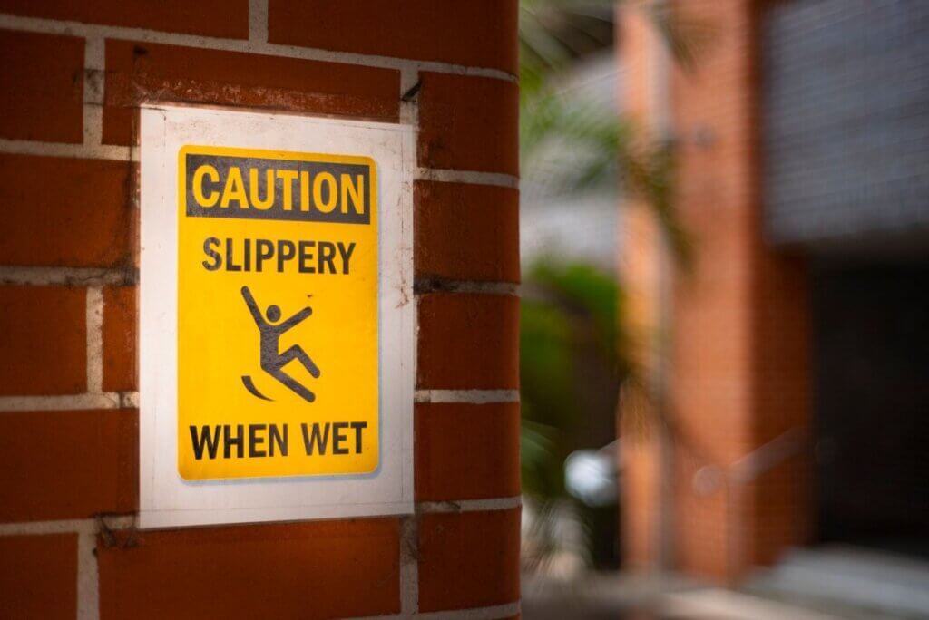 yellow sign on a wall that says slipper when wet