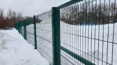 close up shot of a steel fence with snow on background