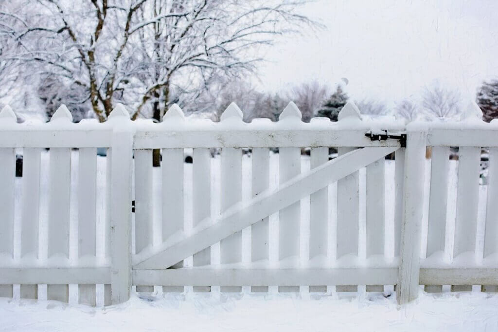 wooden fence with swing gate covered in snow