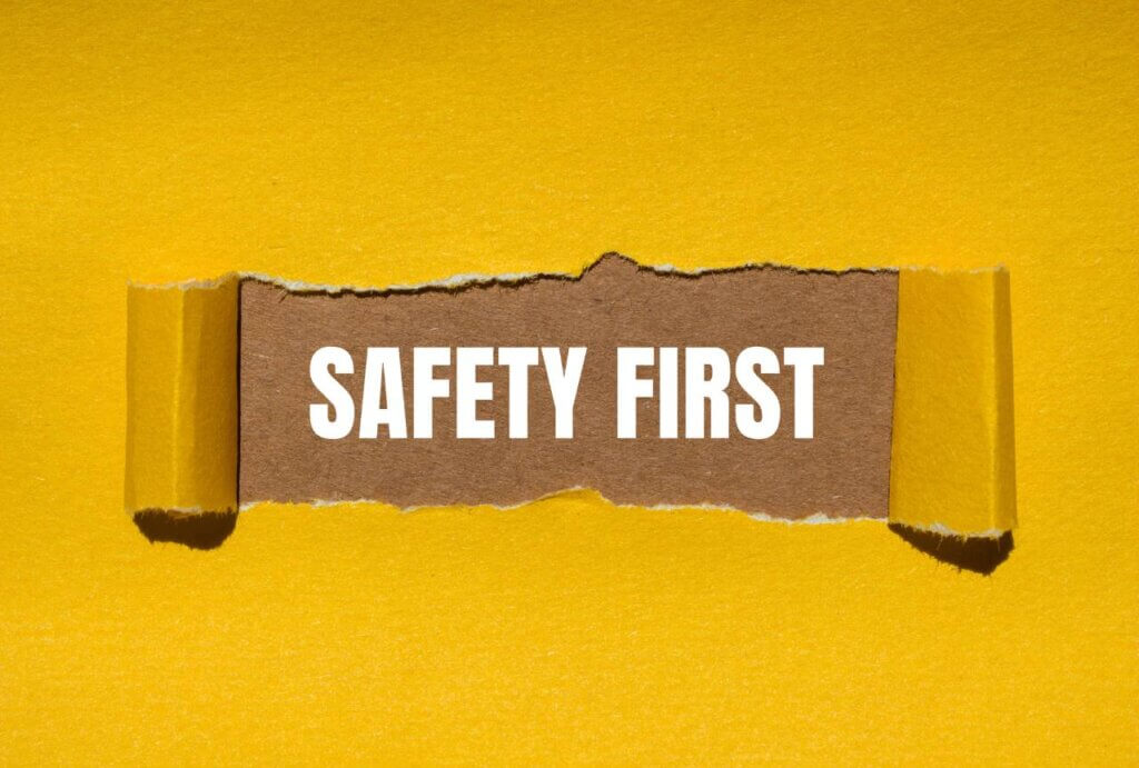 Safety first message written on ripped torn yellow paper with brown background