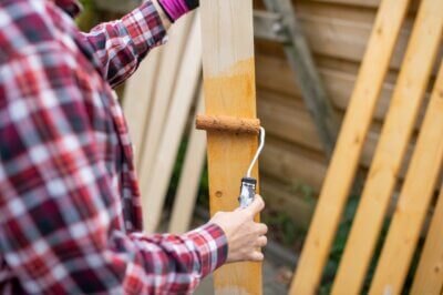 man staining wooden planks