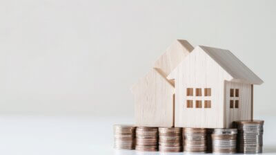 A wooden house with a pile of coins surrounding it