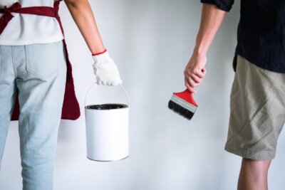 two men holding a can of paint and a paint brush