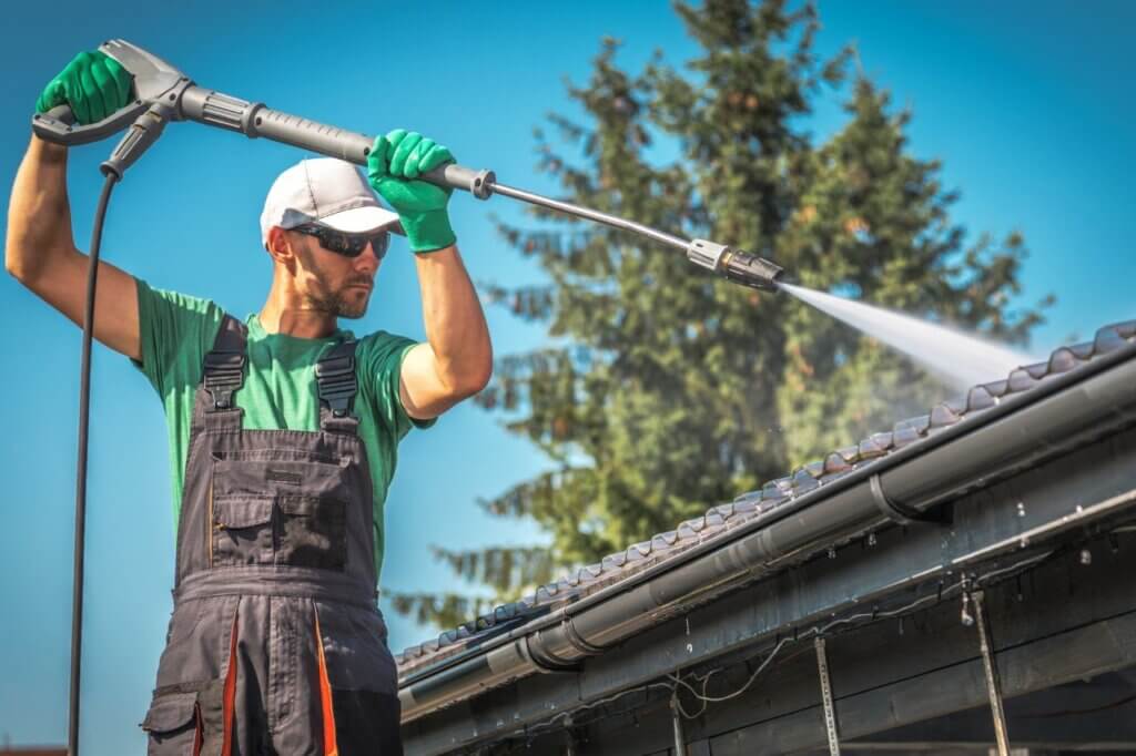 man pressure washing a roof